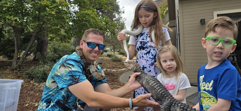 James McNamara showing a dwarf caiman to three children