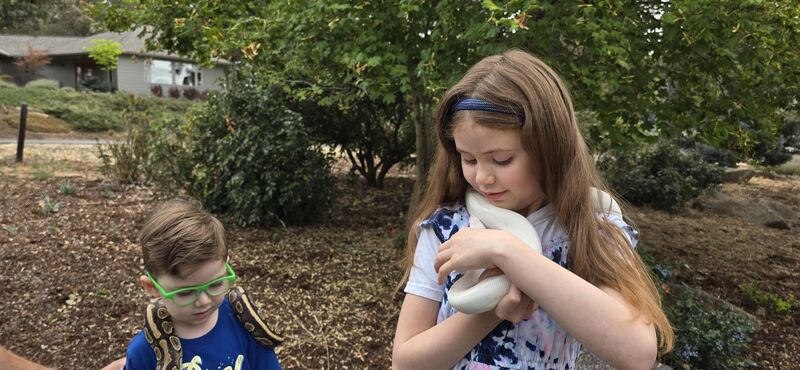 Two children each holding a snake