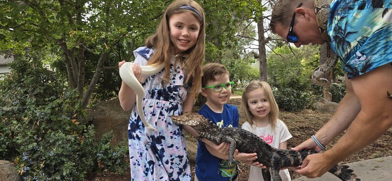 Three children holding a dwarf caiman together